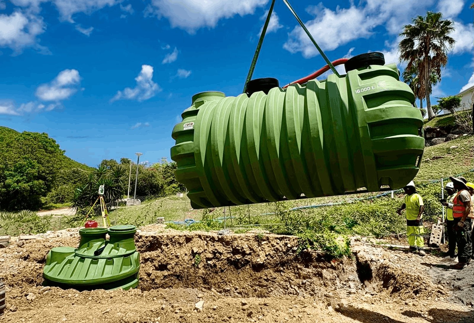 Crane lowering a 16,000 litre green treatment tank on a hillside site